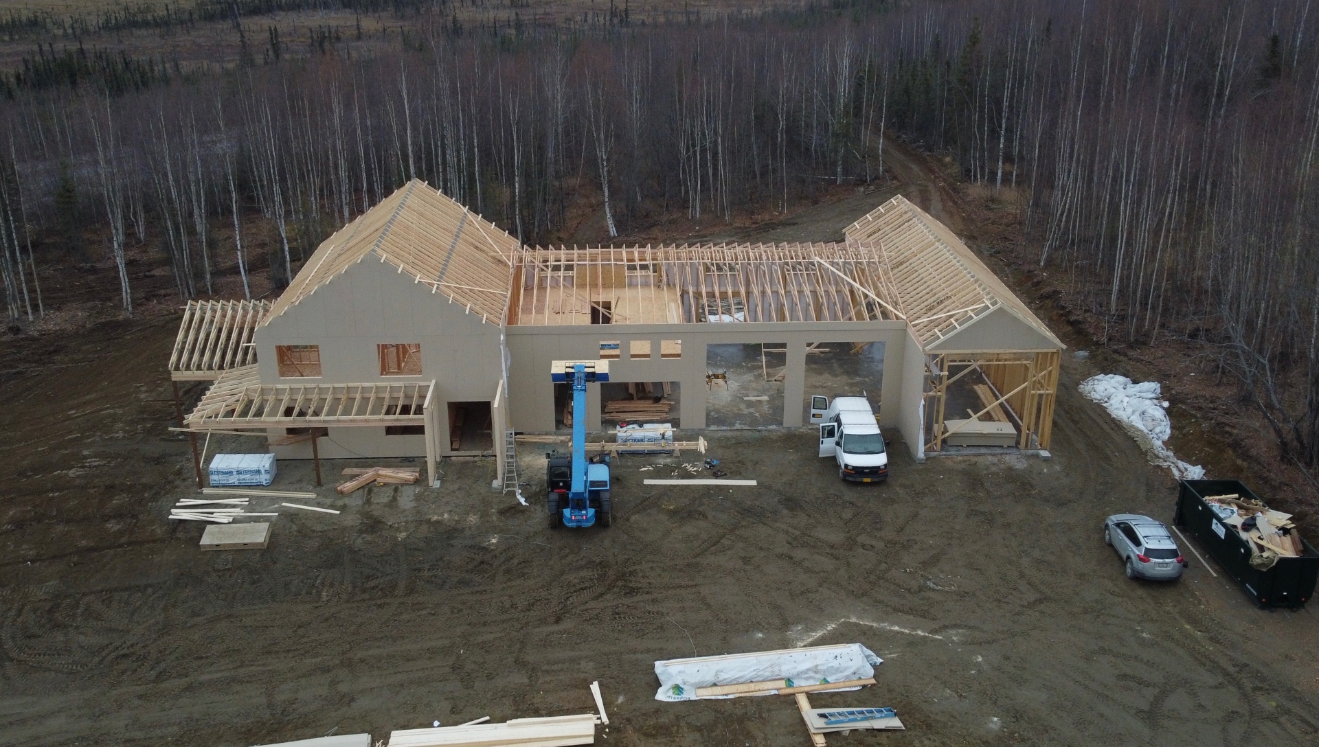 Aerial view of a large single-story custom home framed with rafters set