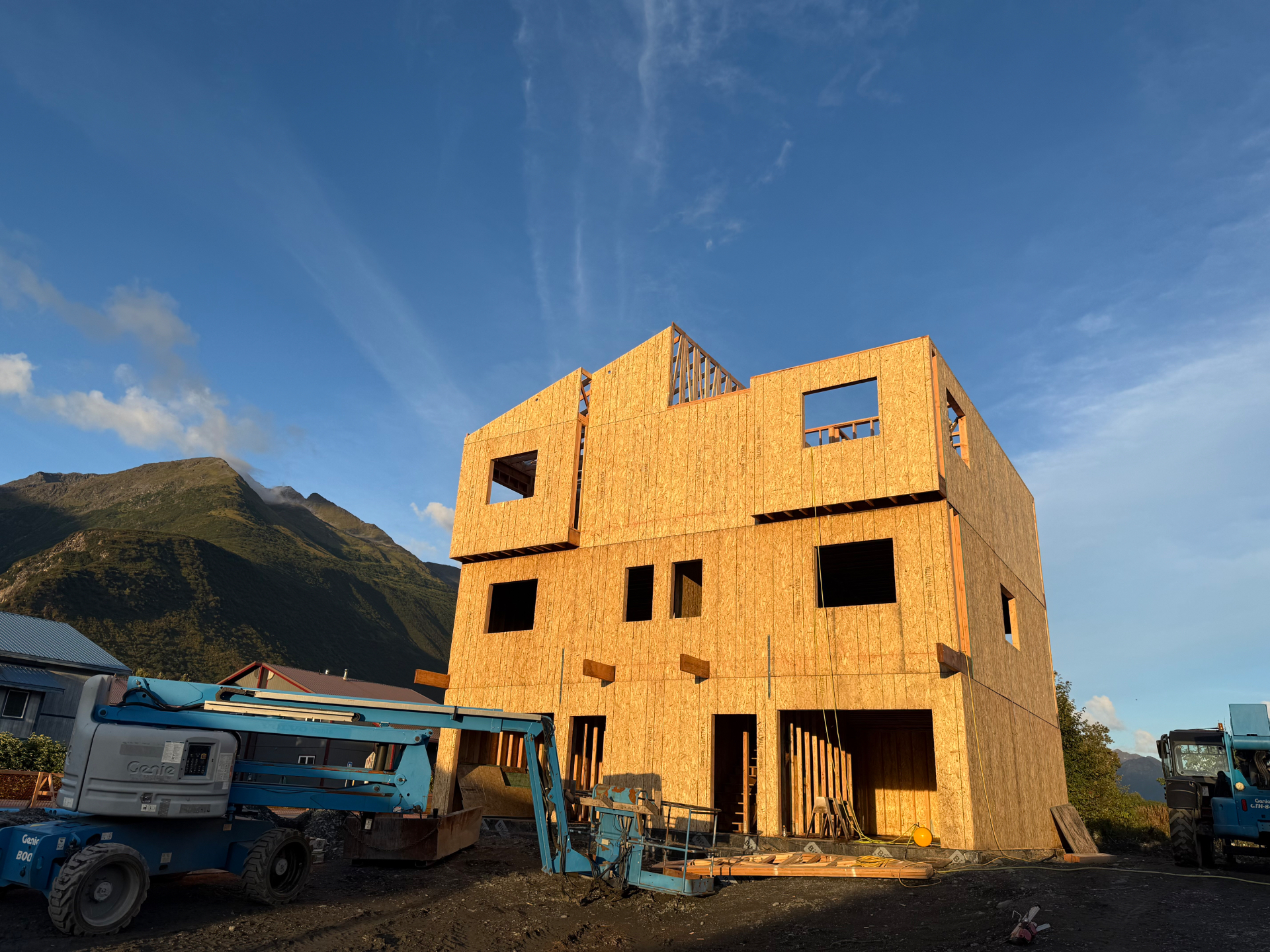 Multi-story sheathed wood building under construction with lifts
