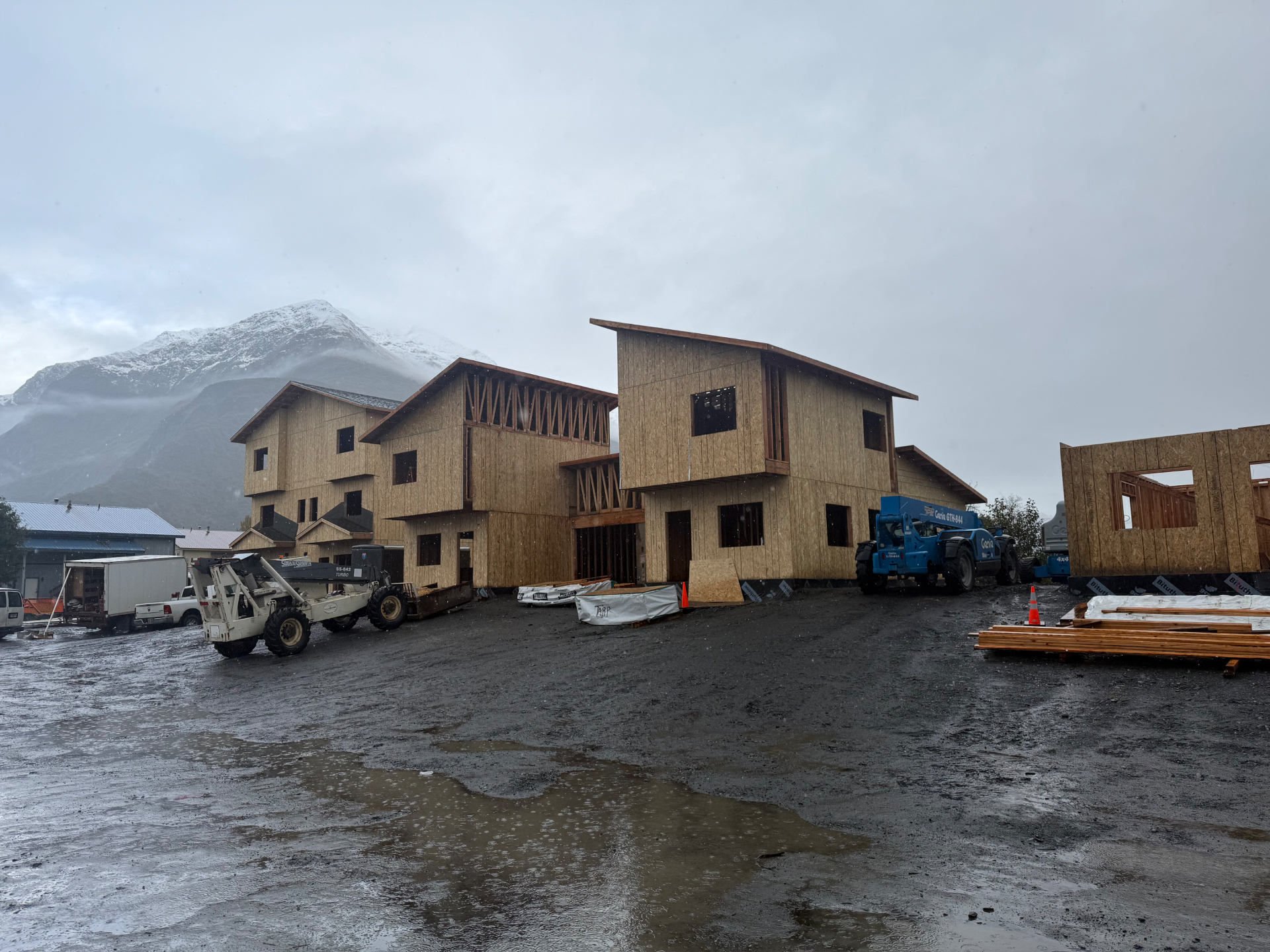 Multi-unit townhome buildings framed and sheathed with mountains in the background